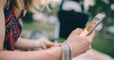 Jovem segurando um celular e assistindo a um vídeo