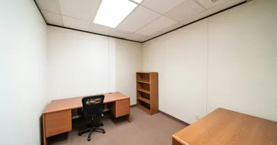 Sala comercial vazia com uma mesa de escritório, cadeira e estante, pronta para ser ocupada