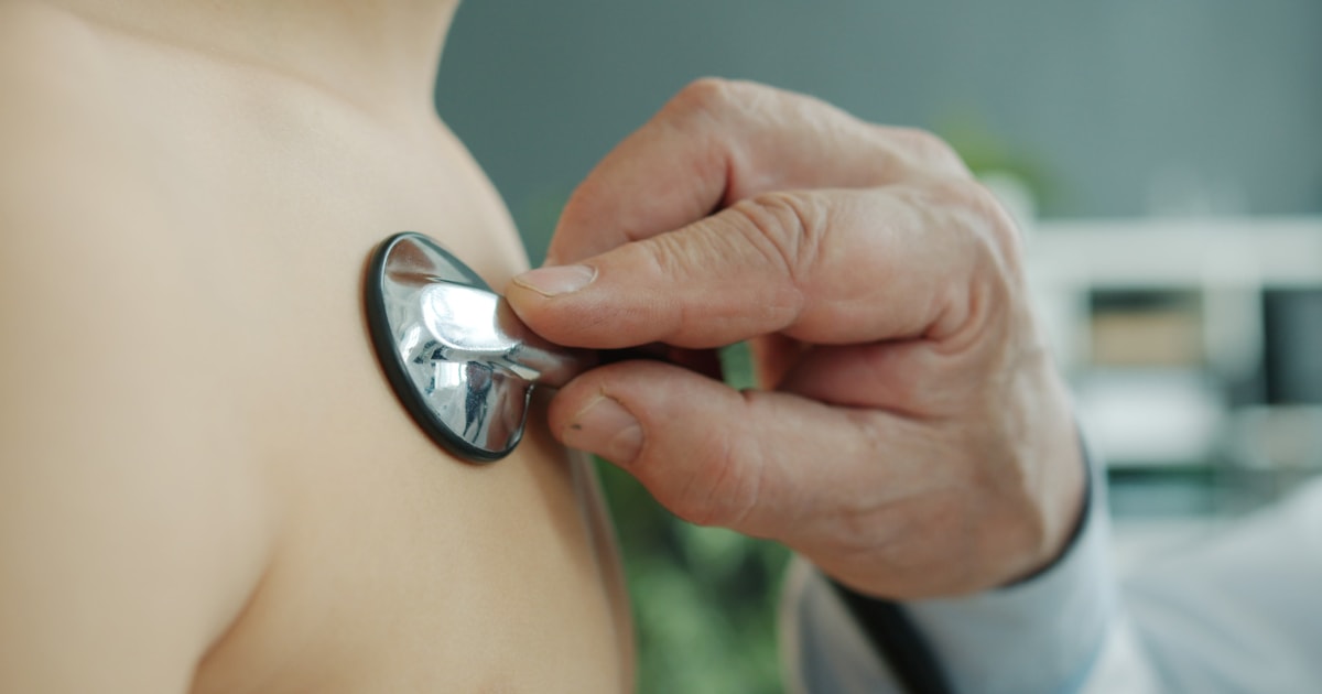 Médico examinando o tórax de um paciente com estetoscópio, em consulta presencial