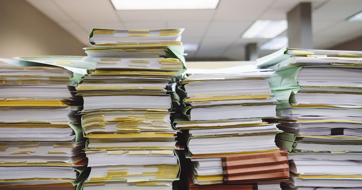 Pilhas de pastas e documentos de papel empilhadas em um escritório