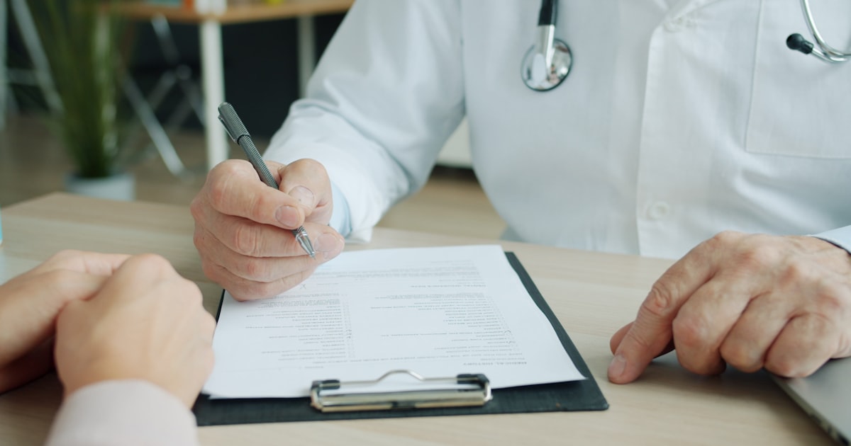 Médico anotando informações em prancheta durante consulta com paciente
